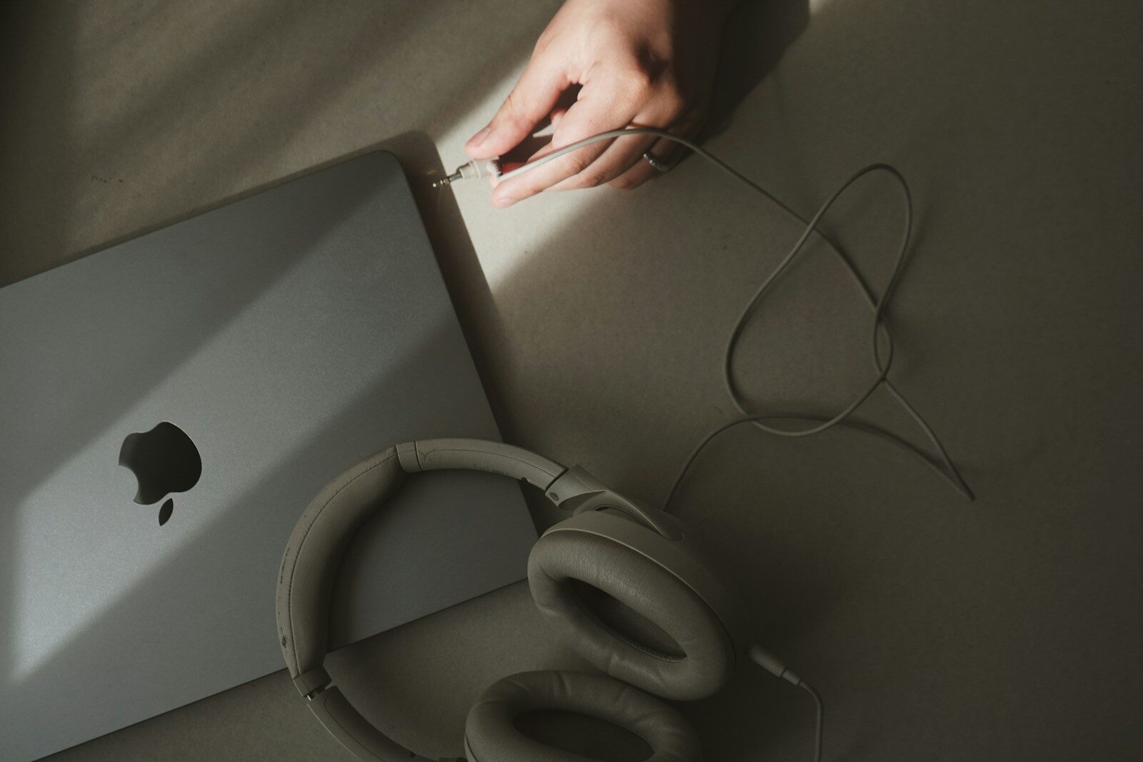 Photo by Daria Glakteeva A person holding a laptop computer next to a pair of headphones