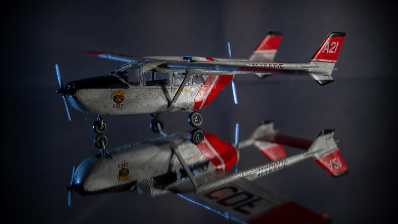A small white and red airplane with its reflection.