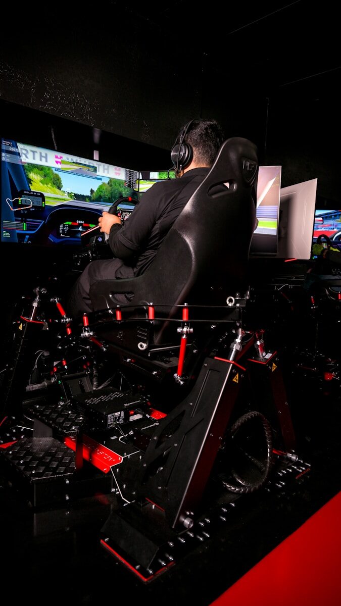 Man plays racing simulator with multiple screens.